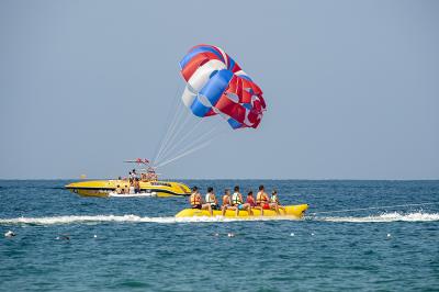 Tourists getting on a yellow banana boat in the sea and tourists doing parasailing